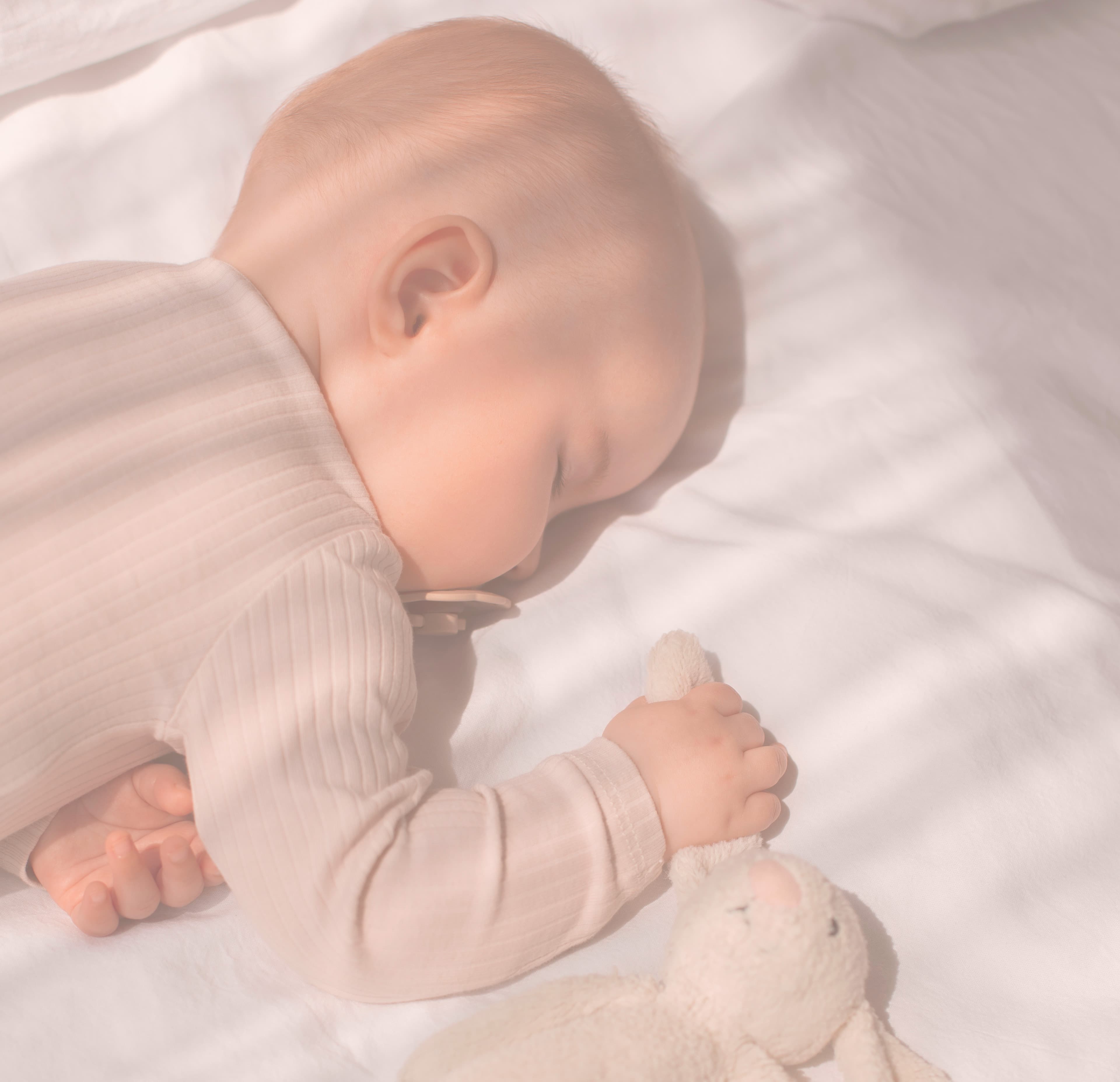 Nouveau-né paisiblement endormi, prêt à accueillir les cadeaux de sa liste de naissance Kikinous